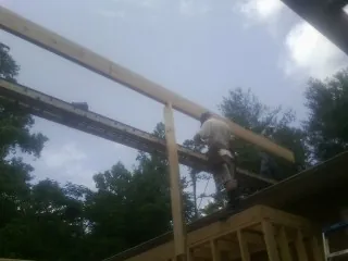 Carpenter setting a ridge beam over a new addition frame — Ice Dam Removal by Roofing Brothers in Lake Andes