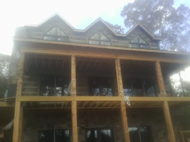 Dormers and porch framing on a large log home under construction — Roof Coating work by our crew in Lake Andes