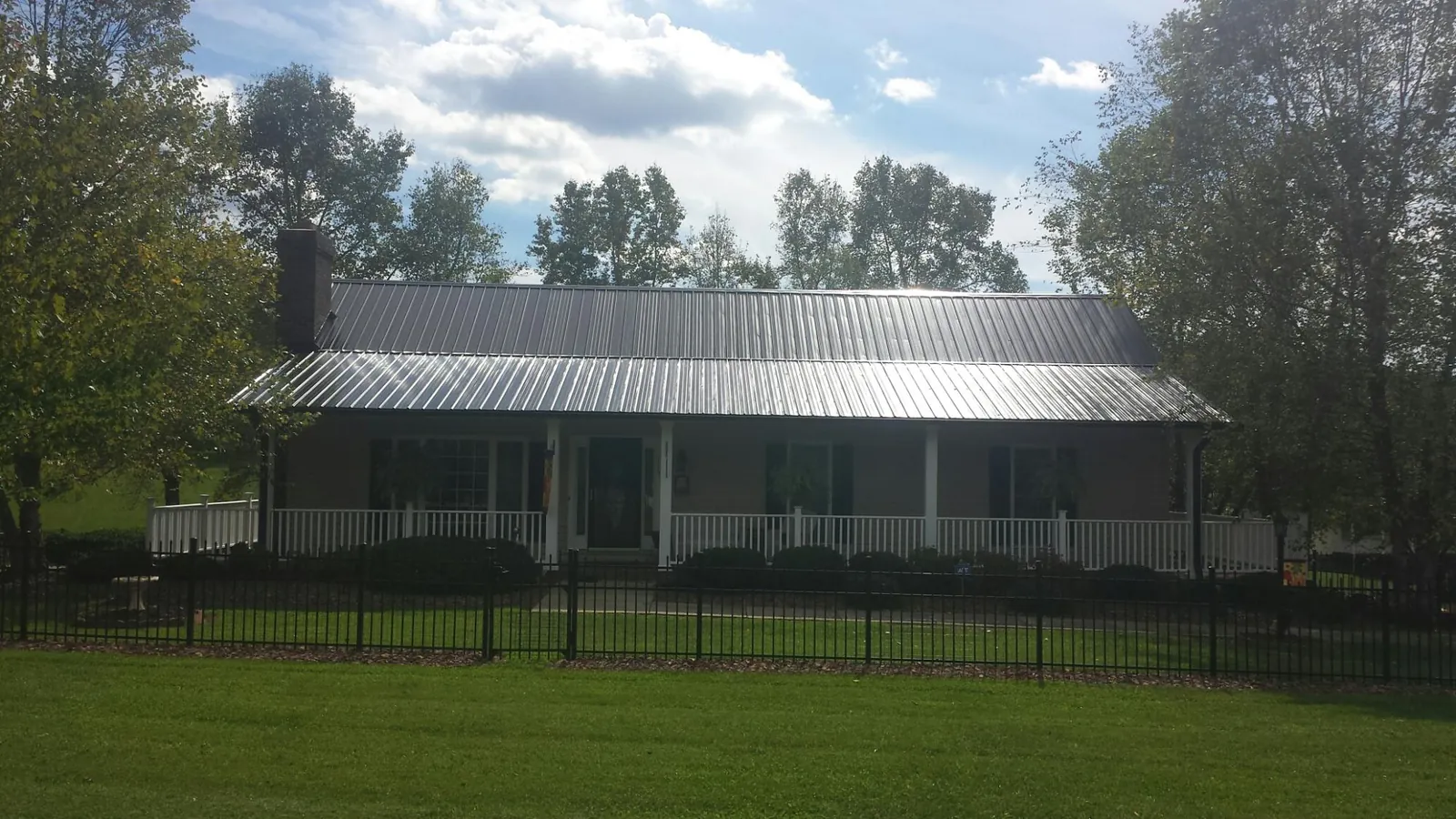 Gray metal roof on a brick ranch with a full width front porch — Gutter Guard Installation work by our crew in Lake Andes