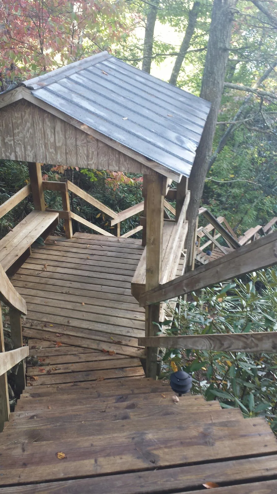 Metal roofed shelter over wooden steps on a wooded walkway — Skylight Repair & Installation work by our crew in Lake Andes