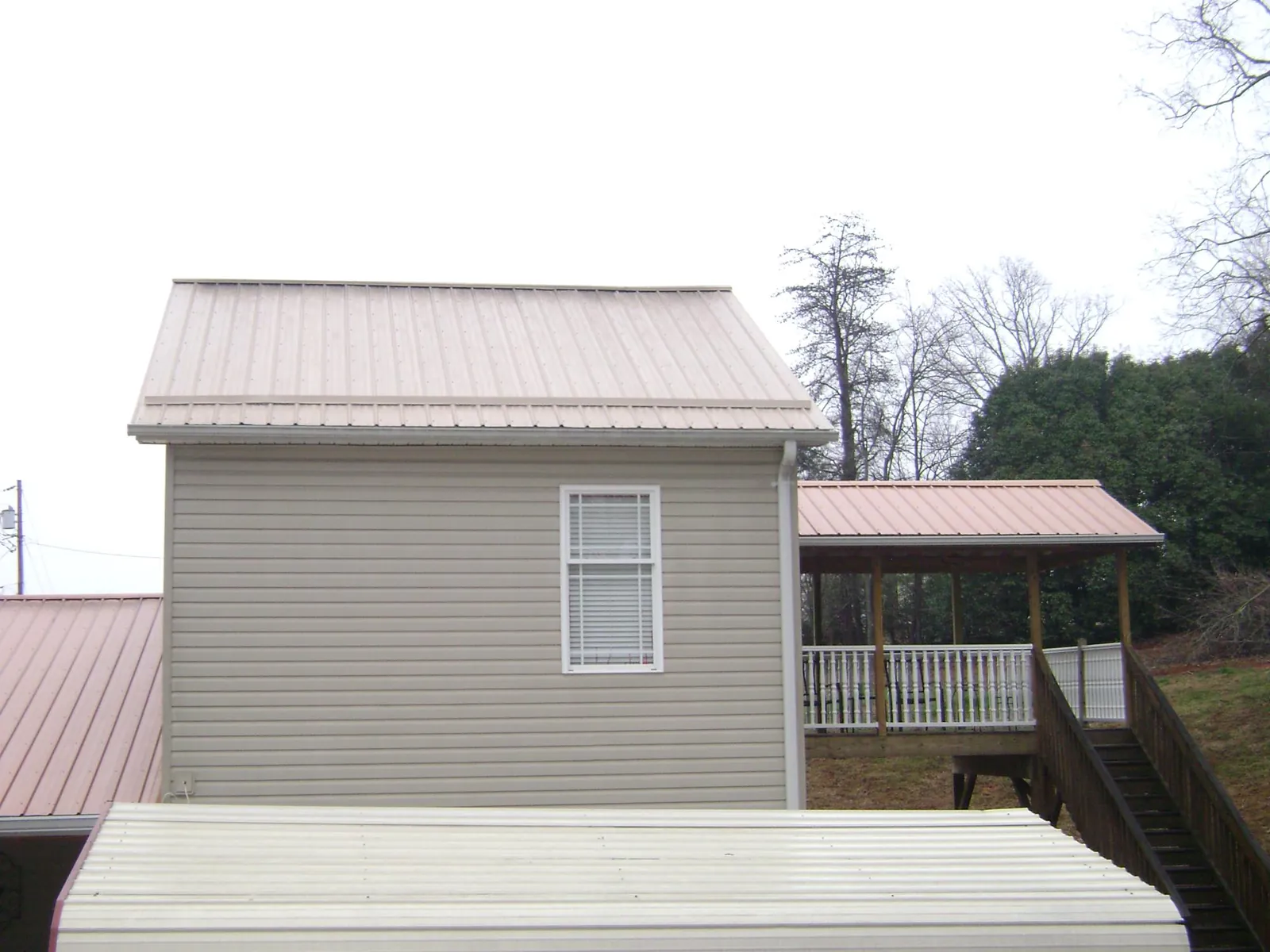 Tan metal roofs on a two story addition and attached porch, from a Roof Replacement job in Lake Andes