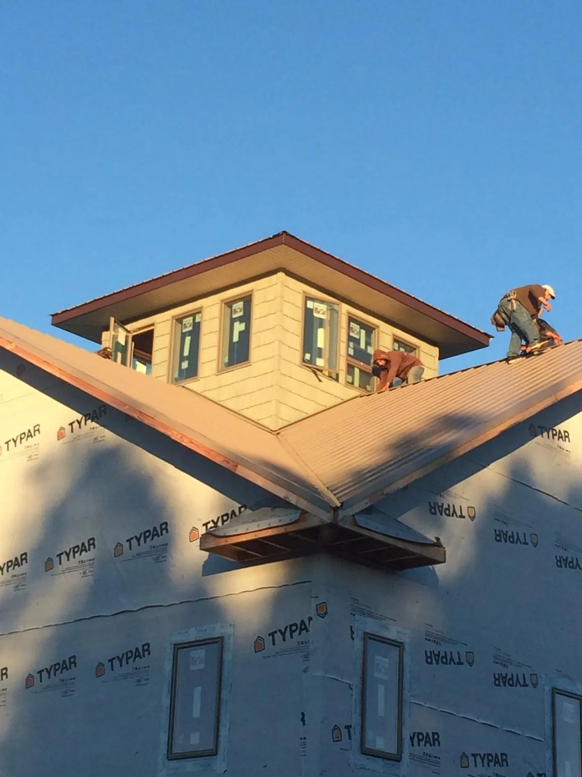 Roofers working around a rooftop cupola on a new metal roof at sunset — Roof Waterproofing in Lake Andes by Roofing Brothers